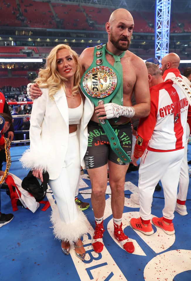 Tyson Fury celebrates his victory with his wife, holding the WBC World Heavyweight Championship belt.