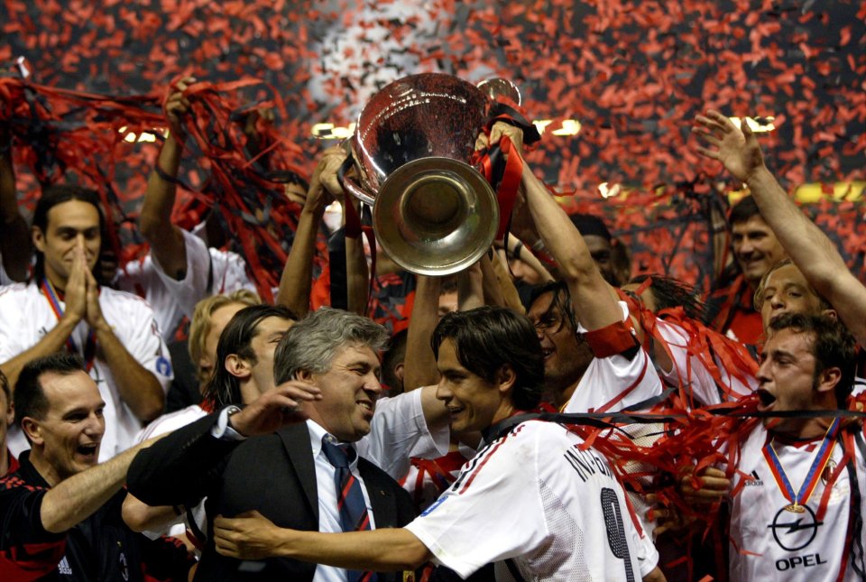 AC Milan manager Carlo Ancelotti (L) embraces striker Filippo Inzaghi (R) as the Champions League trophy is hoisted over their heads by other team members in Manchester May 28, 2003. AC Milan defeated Juventus 3-2 in the final in a penalty shoot out. REUTER/Alessandro Bianchi