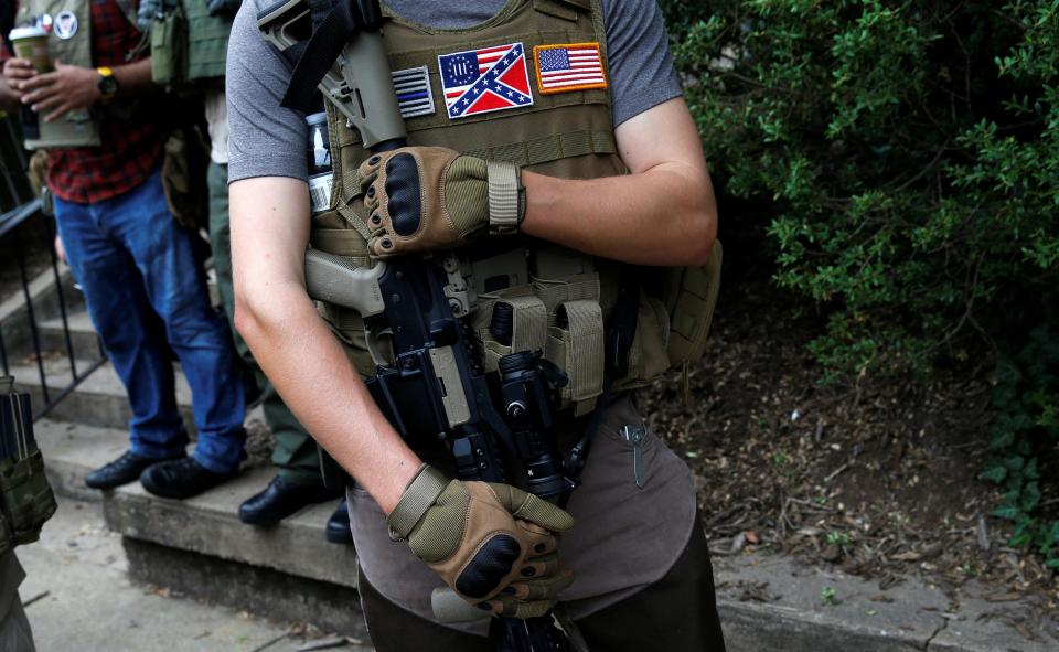  A right-wing militia member, wearing a Confederate badge, pictured with a high-powered firearm