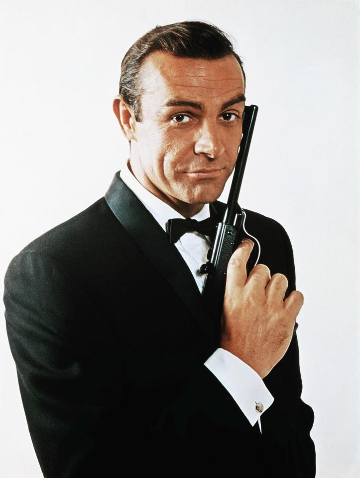 Sean Connery, as James Bond, caressing the barrel of a gun against the side of his face