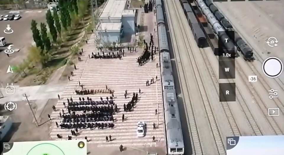 A still from drone footage which claims to show Uighur prisoners being piled onto trains in China