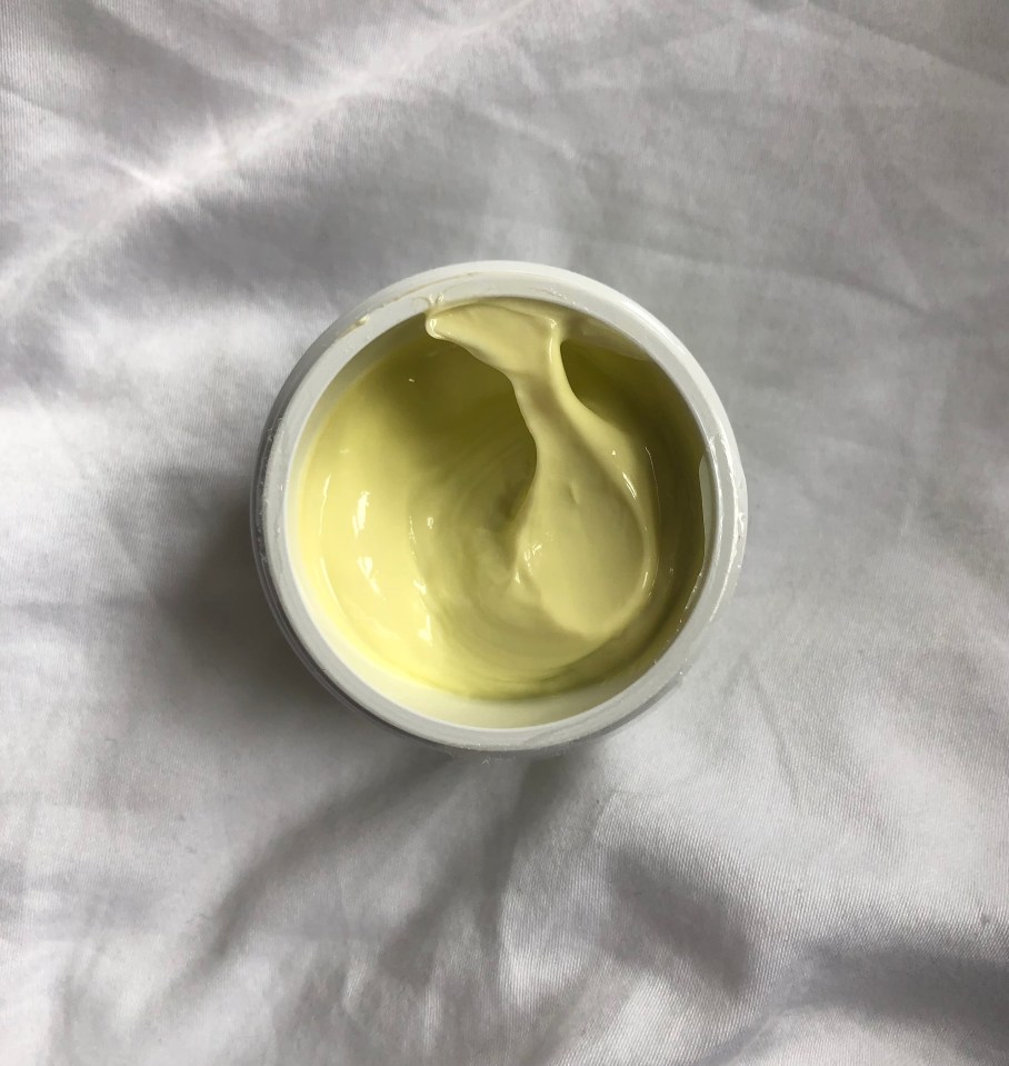Pale yellow cream in a white jar.