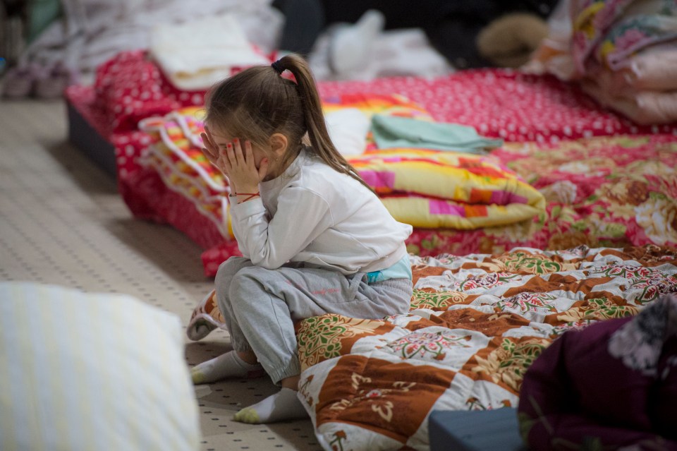 A child refugee covers her face after crossing the border into Romania