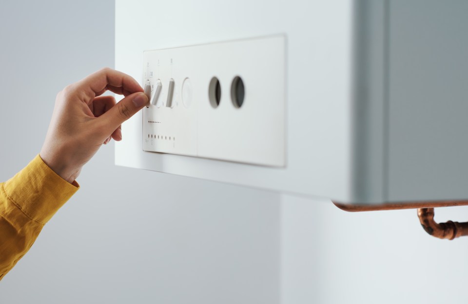Woman adjusting the temperature settings on a home boiler.