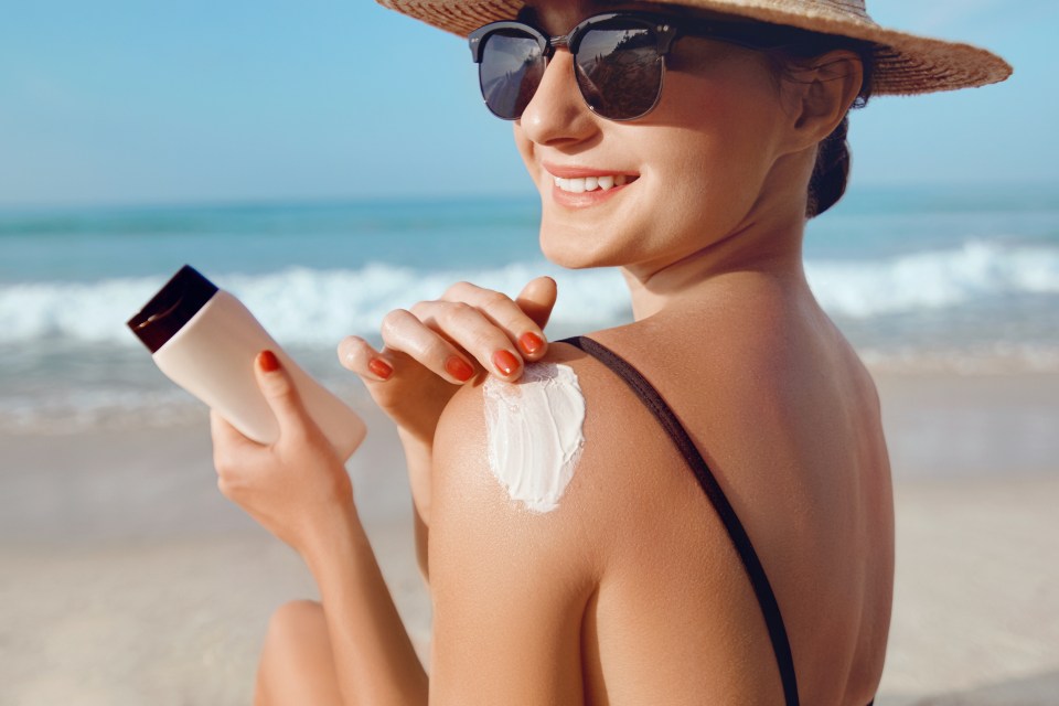 Woman applying sunscreen at the beach.