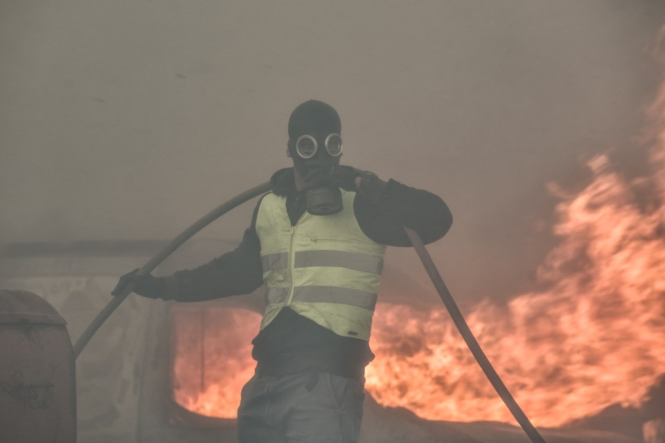 A local resident tries to battle flames near Athens