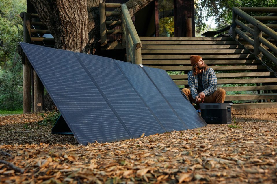 Man connecting portable solar panel to power station.
