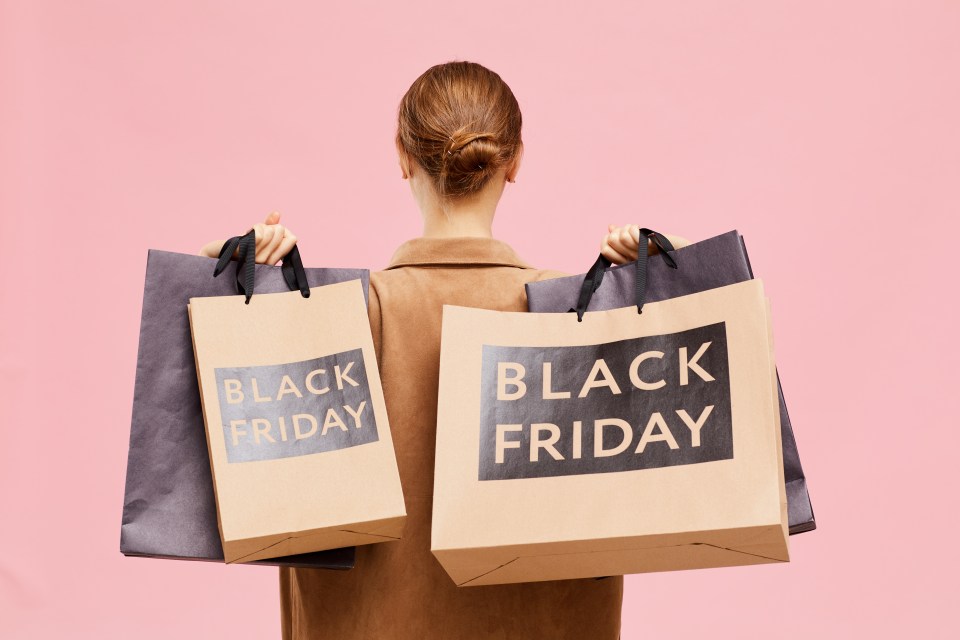 a woman is holding three black friday shopping bags
