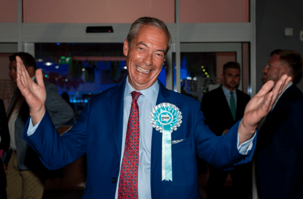 a man in a blue suit has a green badge on his chest