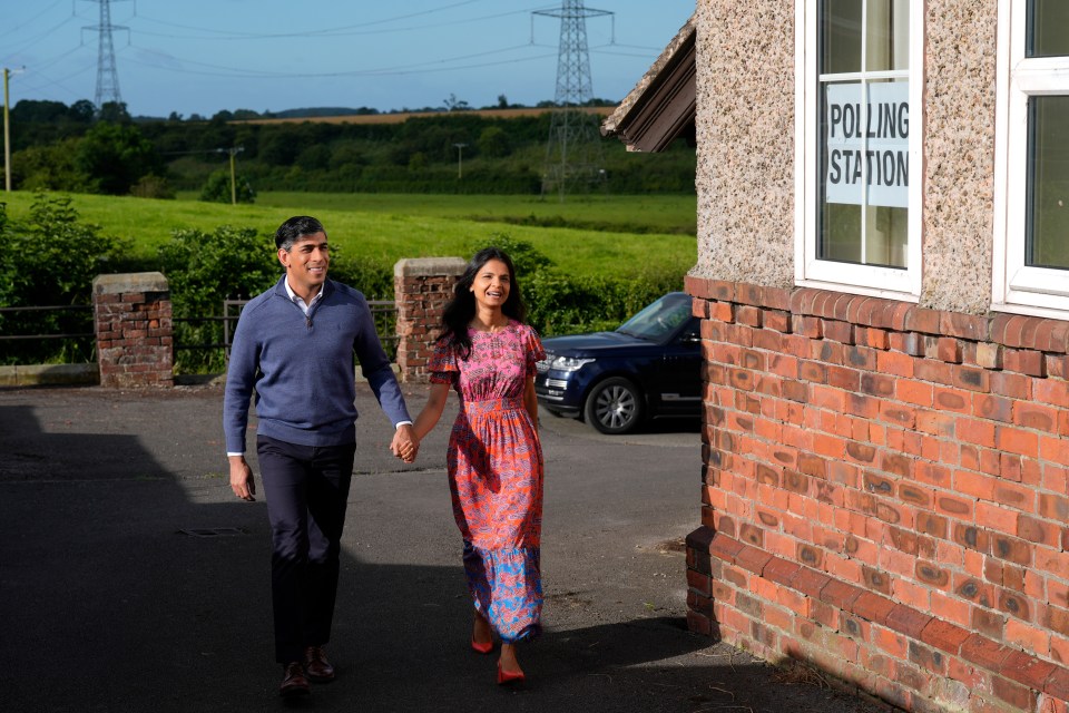 a man and woman are walking in front of a polling station