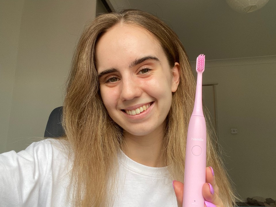 Person holding a pink Hismile electric toothbrush.