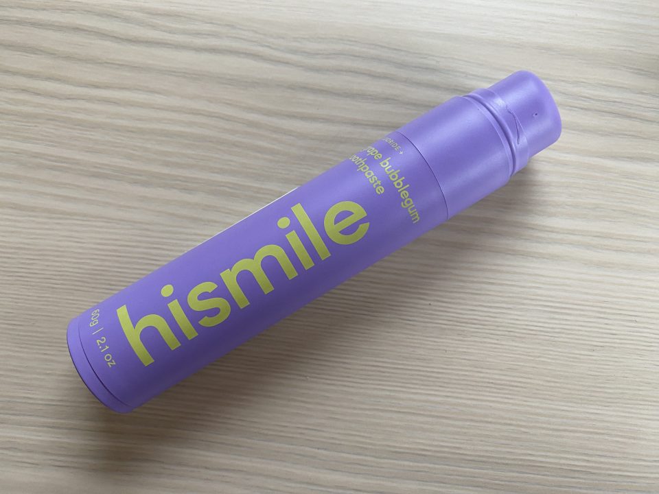 a purple bottle of hismile toothpaste on a wooden surface