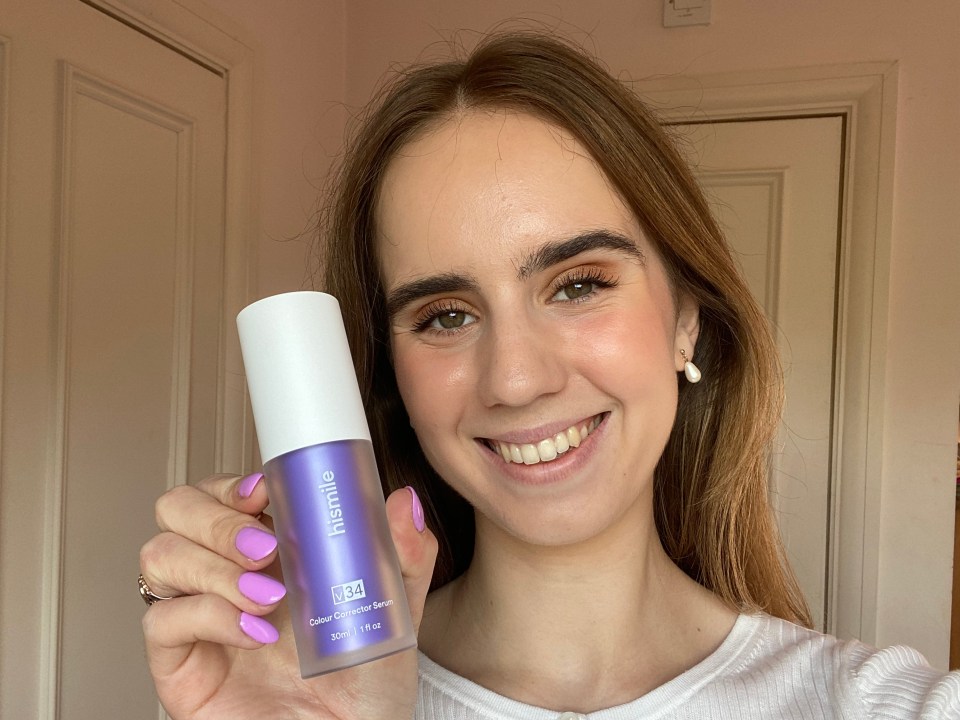 a woman with purple nails is holding a bottle of hismile