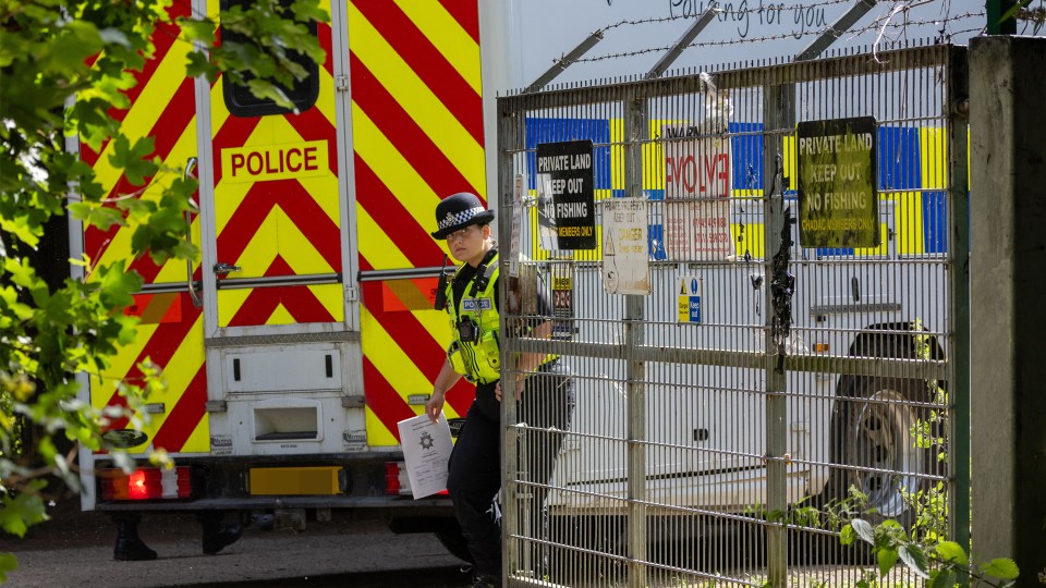 a police officer stands in front of a fence with a sign that says private land keep out of fishing