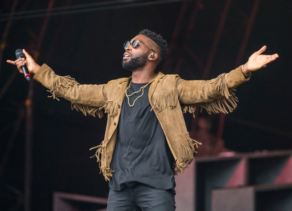 a man singing into a microphone with his arms outstretched