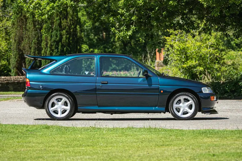 a blue sports car is parked in a grassy area