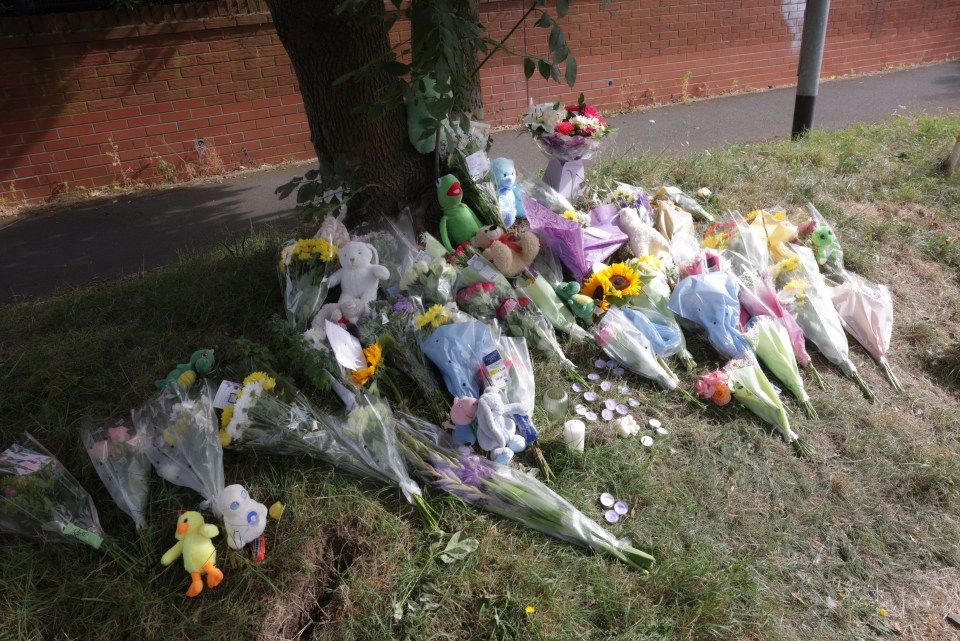 a bunch of flowers and stuffed animals under a tree