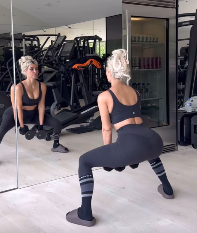 a woman squatting in front of a mirror in a gym