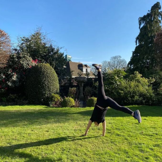a woman is doing a handstand in the grass in front of a house