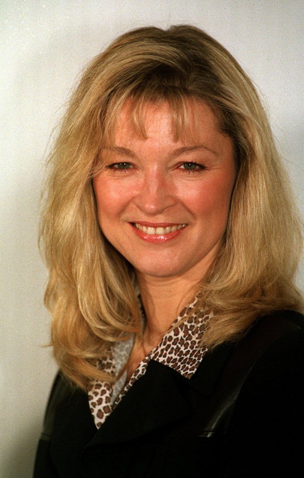 a woman with blonde hair and a leopard print collar smiles for the camera