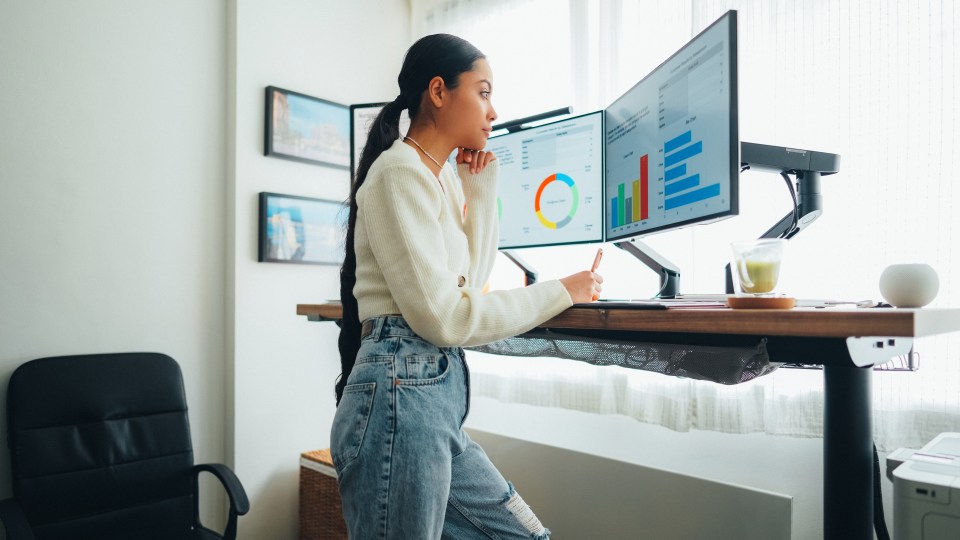 a woman is standing at a desk looking at a computer screen