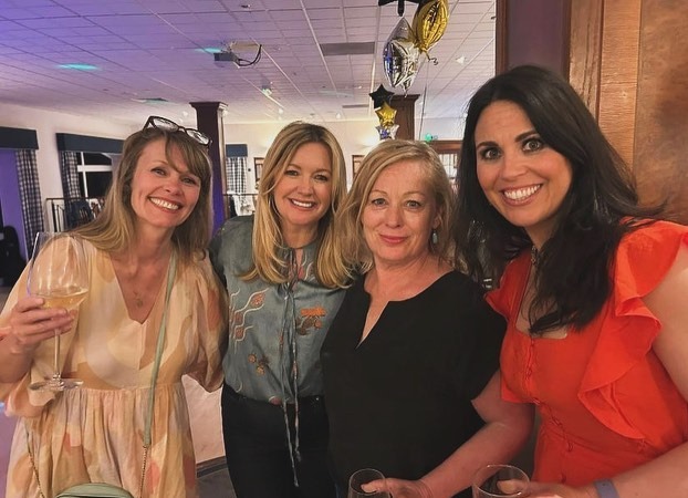 a group of women are posing for a picture and one of them is holding a glass of wine