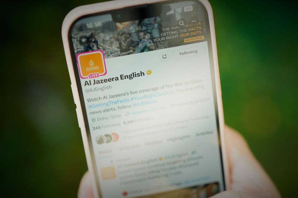 a close up of a cell phone displaying the twitter page of al jazeera english