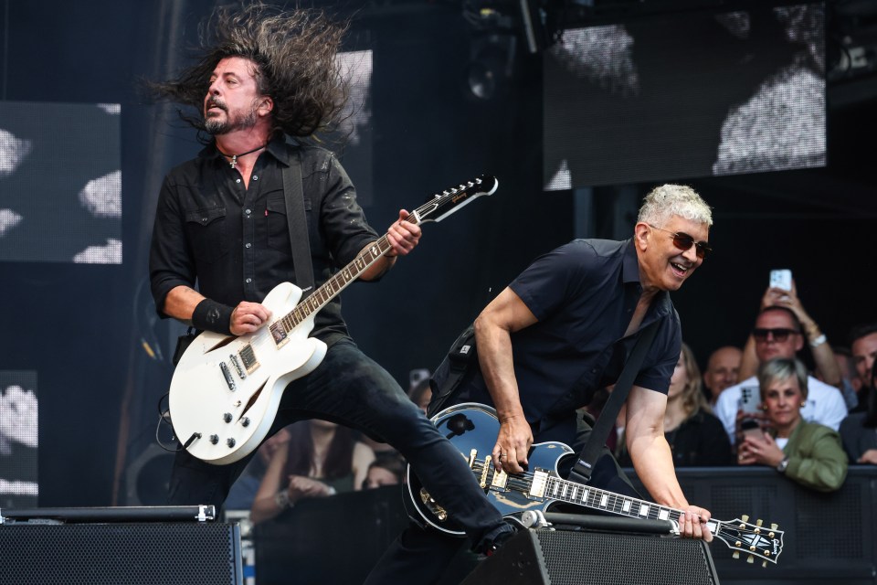 a man playing a guitar next to another man playing a guitar