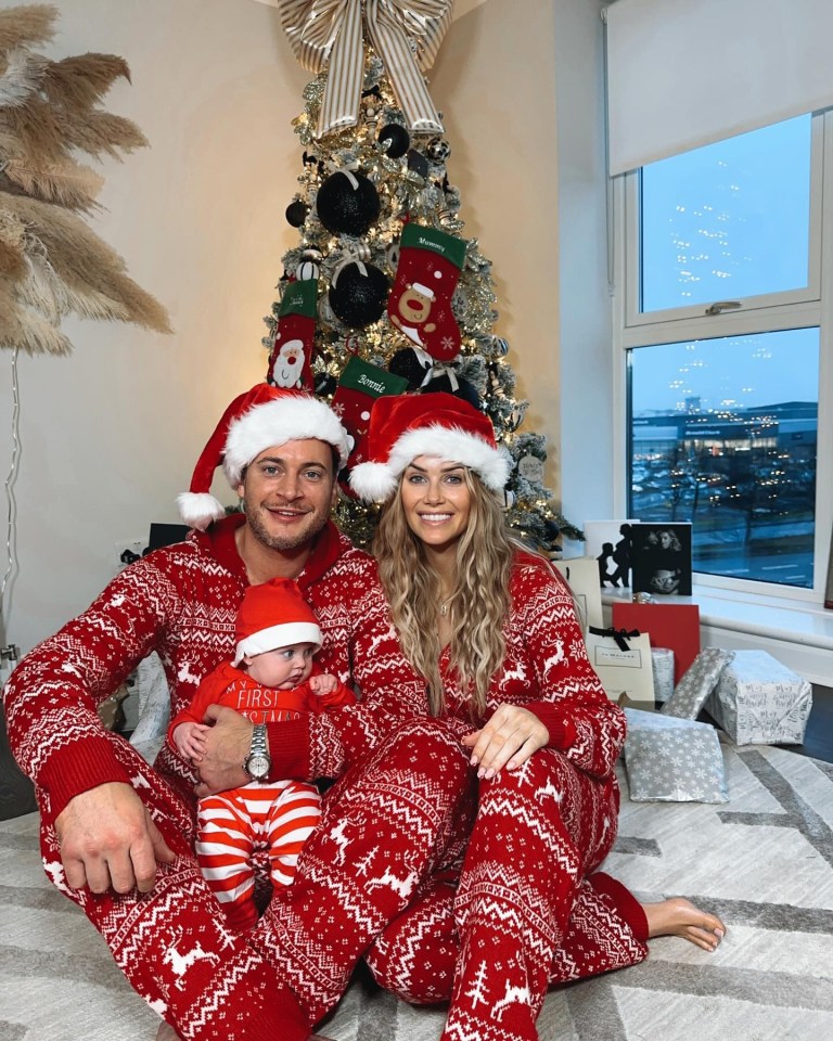 a man and woman holding a baby standing next to santa