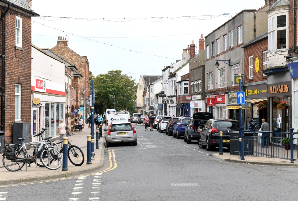 a row of cars are parked on the side of a street in front of a shop called mainroads