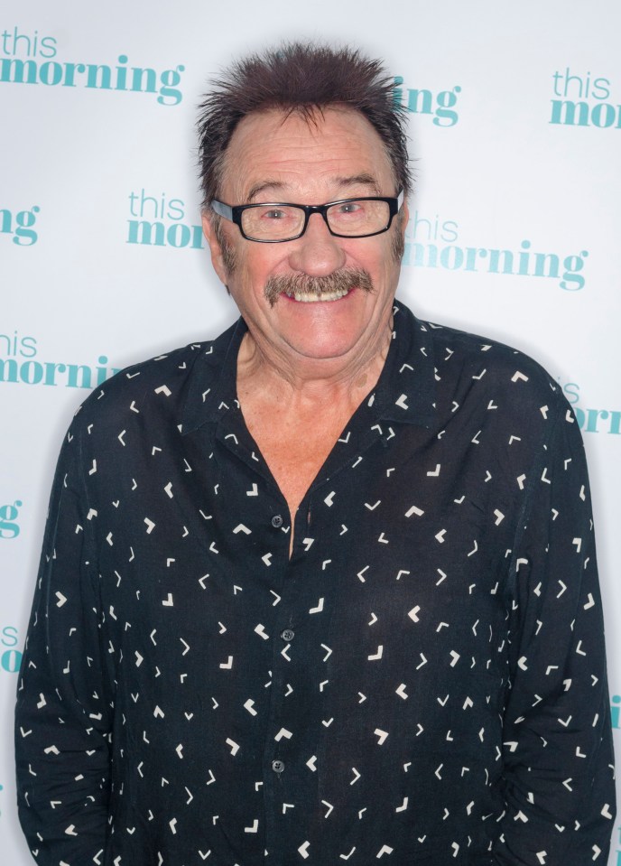 a man with glasses and a mustache stands in front of a wall that says this morning