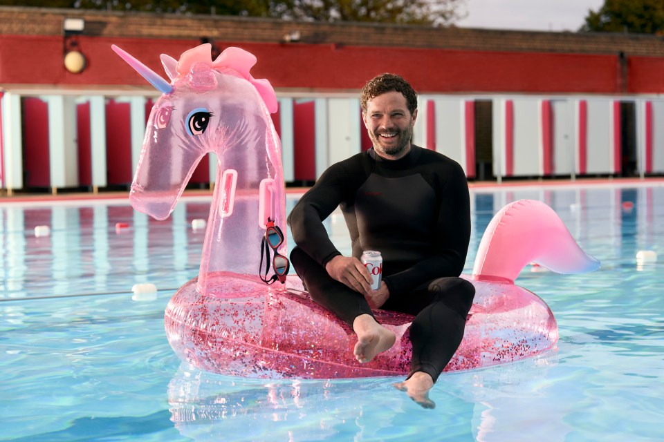 a man sits on a pink unicorn float in a pool