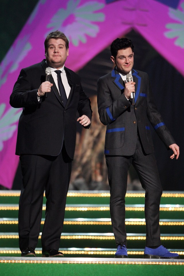 two men stand on a stage with microphones in their hands
