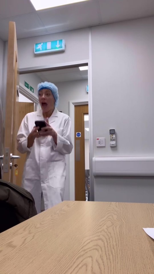 a woman in a lab coat and surgical cap is looking at her phone