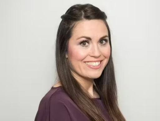 a woman with long hair is smiling and wearing a purple shirt .