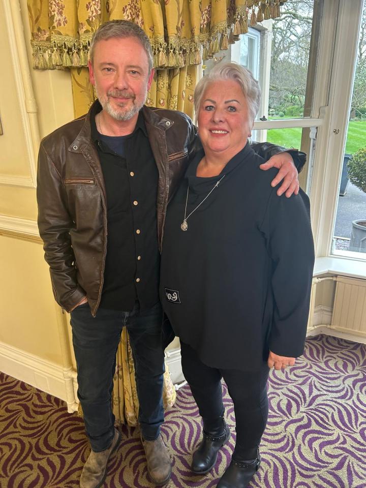 a man in a leather jacket stands next to a woman in a black shirt