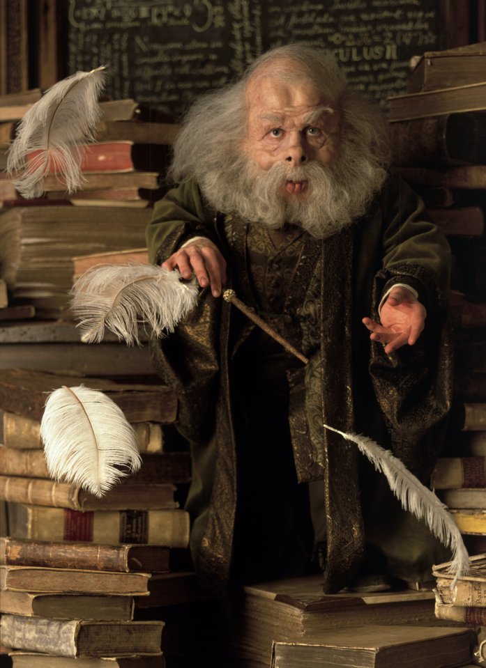 a man with a beard is sitting on a pile of books and holding a wand