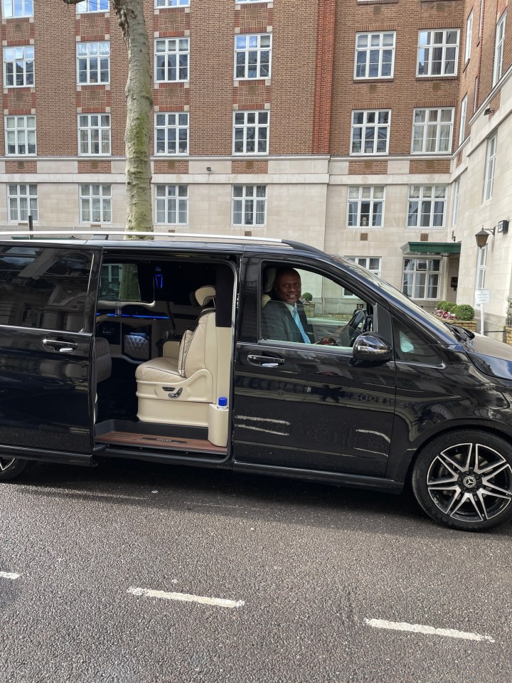 a man sits in the driver 's seat of a black van