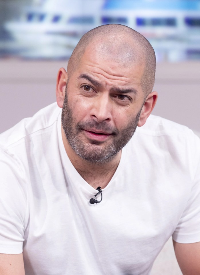 a bald man with a beard and a microphone on his neck