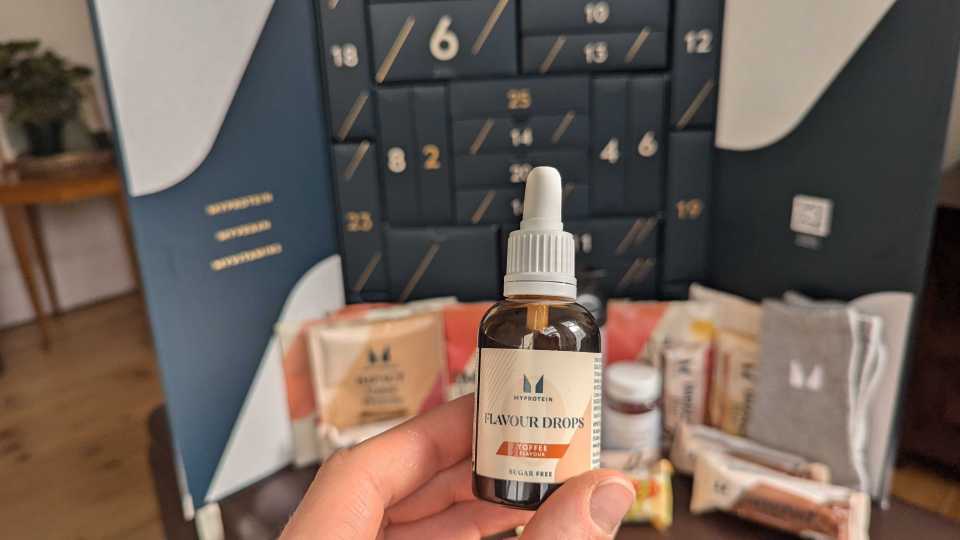 a person holding a bottle of flavour drops in front of a calendar