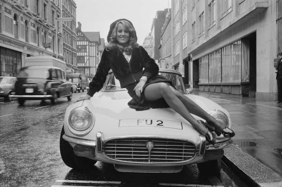 a woman sits on a car with the license plate fu2