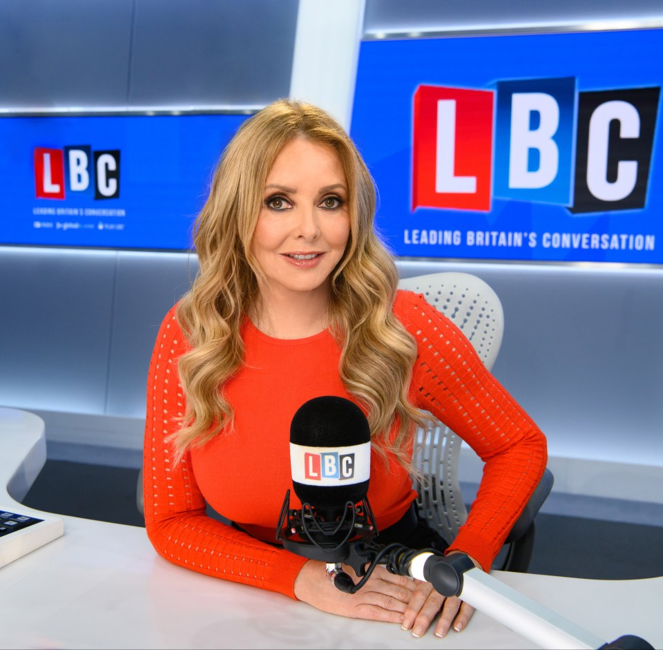 a woman sitting in front of a lbc sign