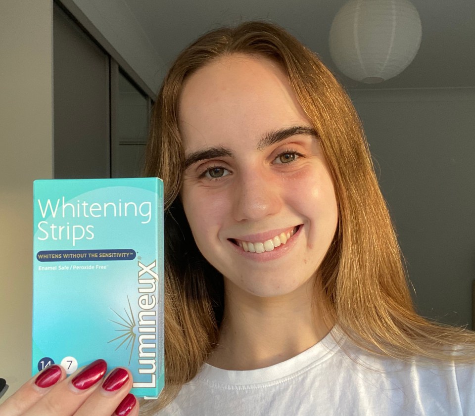 a woman holding a box of lumineux whitening strips