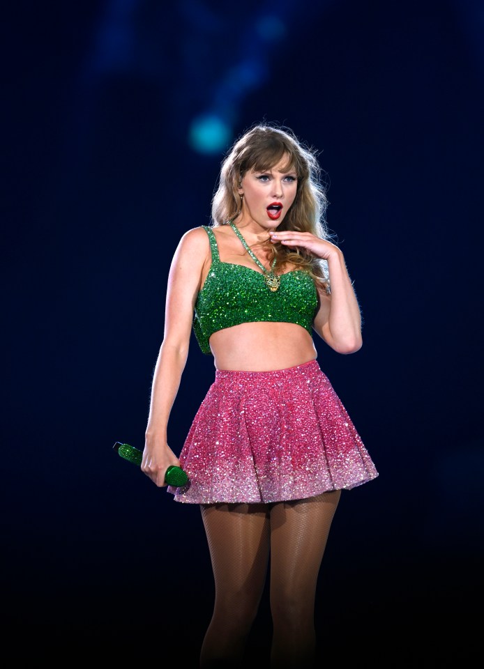 a woman in a green top and pink skirt holds a green microphone