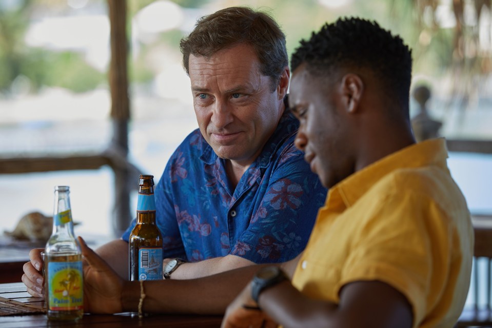 two men sit at a table with a bottle of lemonade