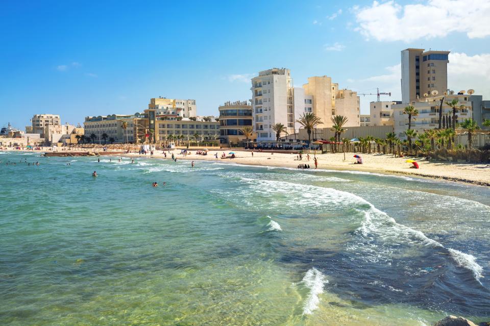 a beach with a lot of people and buildings in the background