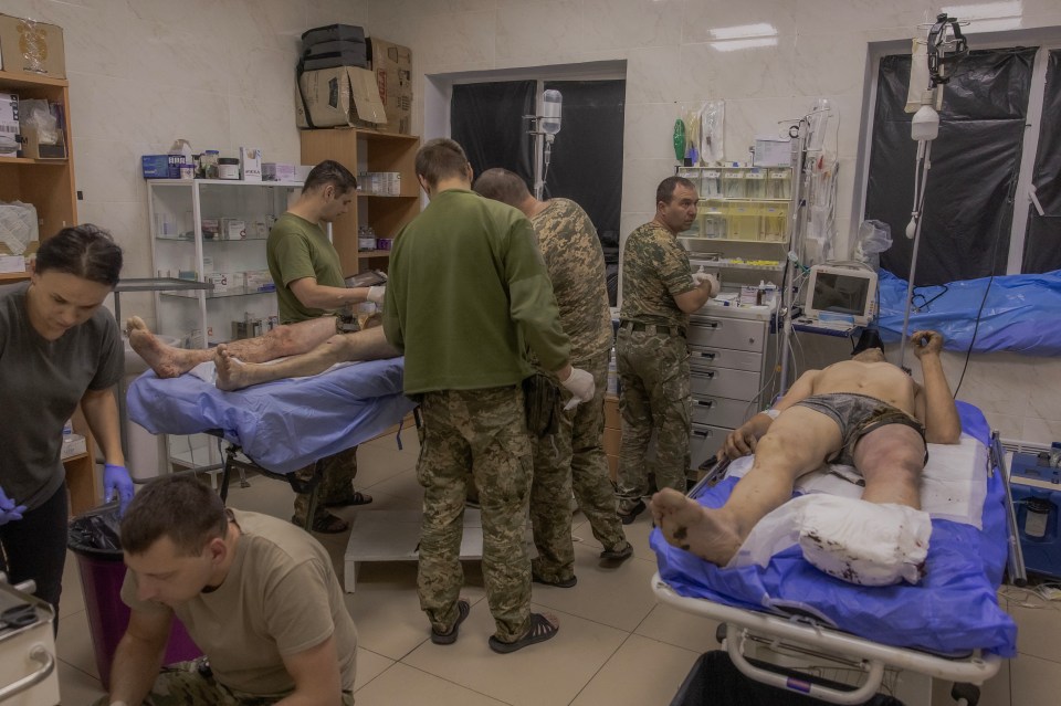 a group of soldiers are standing around a man laying on a stretcher