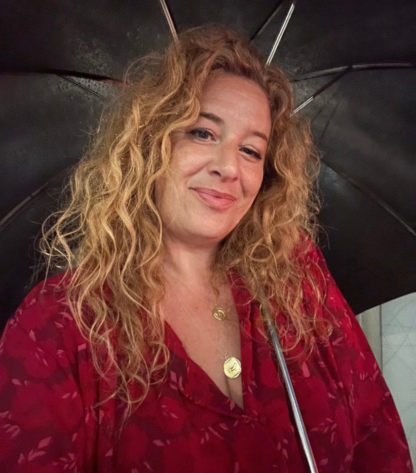 a woman in a red dress is holding a black umbrella