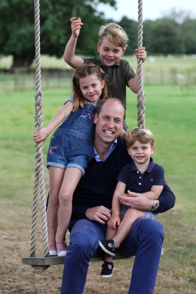 a man sits on a swing with three children behind him