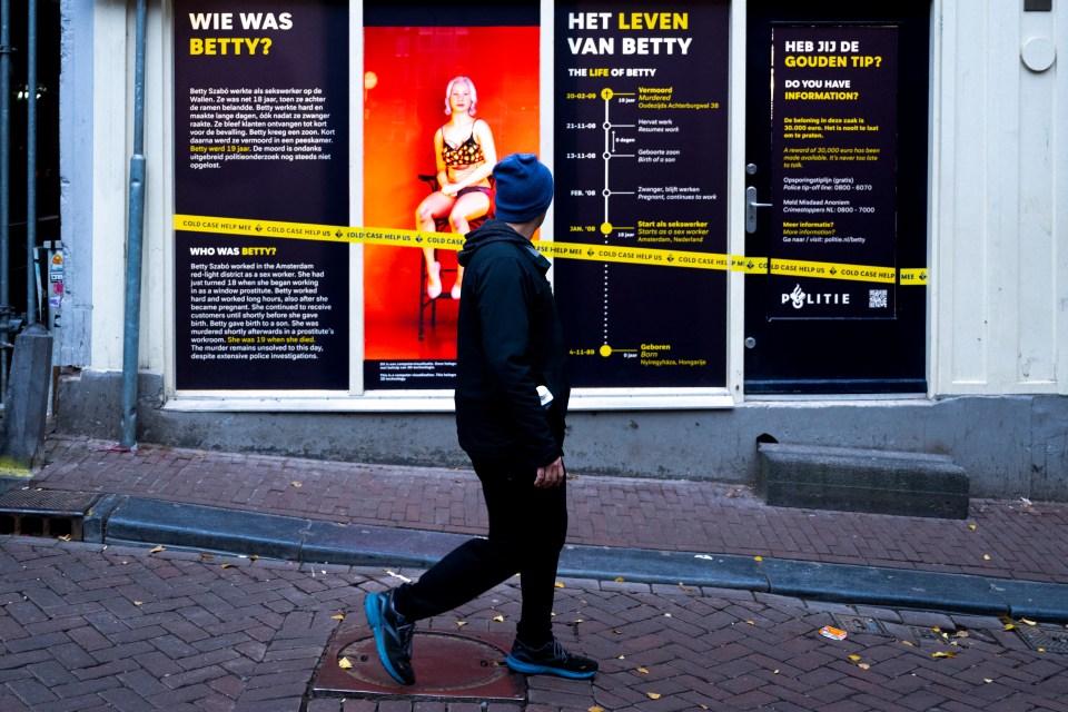 a man walks past a window with a poster that says wie was betty